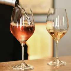 Un verre de vin blanc bouchonné, d'une couleur rosée, est servi dans un verre. Un autre verre de vin blanc est à côté.