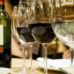 Une bouteille de vin rouge et plusieurs verres remplis de vin à la belle couleur rubis.