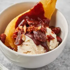 Poire pochée, glace vanille, sauce chocolat et amandes effilées pour une poire Belle Hélène gourmande.