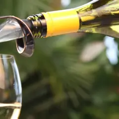 Un vin blanc est versé dans un verre, suggérant le plaisir d'un bon vieillissement du vin.