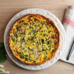 Une appétissante quiche aux légumes, garnie d'épinards et de fromage, prête à être dégustée.