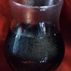 Verre de vin rouge givré, fraîchement sorti du frigo. Les gouttelettes d'eau perlent sur le verre, promettant une dégustation rafraîchissante.