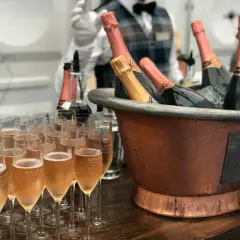 Une belle quantité de vin pour un mariage, avec des flûtes remplies de champagne et des bouteilles au frais dans un grand seau en cuivre.