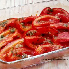 Tomates au four coupées en quartiers, baignant dans leur jus avec des herbes et de l'ail. Un plat simple et savoureux.