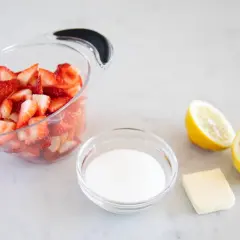 Ingrédients pour un coulis de fraise : fraises coupées, sucre, beurre et citrons.