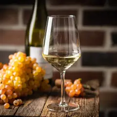 Verre de vin blanc sec, avec des grappes de raisins dorés. Le taux de sucre dans le vin blanc sec est faible, idéal pour accompagner les mets.