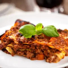 Une part de lasagnes à la bolognaise, garnie de basilic frais. Idéal pour savoir quel vin avec des lasagnes.