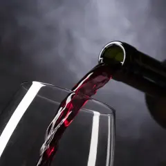 Un vin rouge est versé dans un verre. Parfait pour accompagner un poulet basquaise.