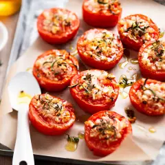 Tomates provençales garnies d'herbes et de fromage, rôties sur une plaque. Un délice méditerranéen.