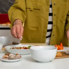 Une personne prépare une salade. Si vous cherchez par quoi remplacer du vin blanc dans une recette, pensez à des ingrédients frais et savoureux comme ceux présentés.