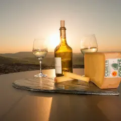 Un coucher de soleil sur le Jura, avec un verre de vin jaune, une bouteille et du fromage Comté. Qu'est-ce que le vin jaune ? C'est un vin du Jura, unique et savoureux.