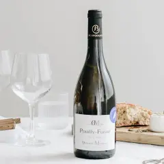 Bouteille de vin blanc Pouilly-Fuissé, prête pour un mariage. Deux verres à vin vides, du fromage de chèvre et du pain sur une planche.