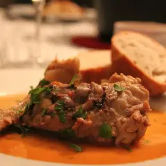 Un plat savoureux d'osso bucco, garni de persil frais, servi avec du pain croustillant. Un délice pour accompagner quel vin avec osso bucco.