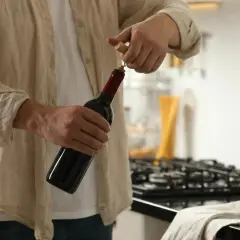 Un homme ouvre une bouteille de vin rouge. Il est temps de conservation rosé ouvert, mais ce vin rouge est prêt à être dégusté.
