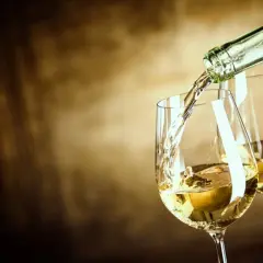 Un vin blanc sucré est versé dans un verre, créant une ambiance chaleureuse et invitante.