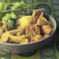 Un bol de colombo de porc, plat épicé et savoureux, garni de coriandre fraîche.