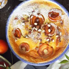 Un délicieux flan aux abricots, saupoudré de sucre glace et parsemé d'amandes concassées, prêt à être dégusté.