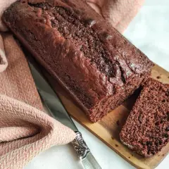 Un délicieux gâteau yaourt chocolat, moelleux et intense, prêt à être dégusté. Une tranche coupée révèle sa texture aérée.