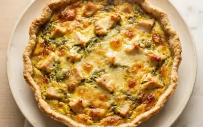 Une délicieuse quiche au poulet, dorée et garnie de morceaux de poulet et de fromage fondant, prête à être dégustée.