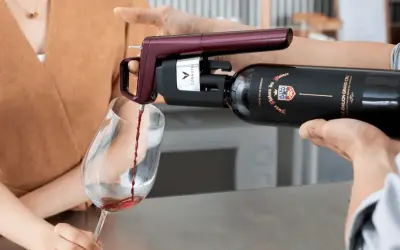 Un appareil Coravin sert un vin rouge d'une bouteille ouverte dans un verre, assurant sa conservation.