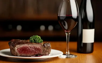 Une succulente entrecôte saignante, garnie d'une touche de persil, accompagnée d'un verre de vin rouge et d'une bouteille.