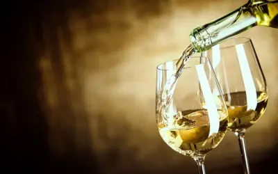 Un vin blanc sucré est versé dans un verre, créant une ambiance chaleureuse et invitante.