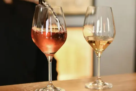 Un verre de vin blanc bouchonné, d'une couleur rosée, est servi dans un verre. Un autre verre de vin blanc est à côté.