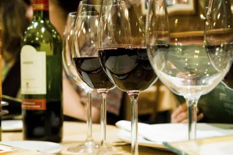 Une bouteille de vin rouge et plusieurs verres remplis de vin à la belle couleur rubis.