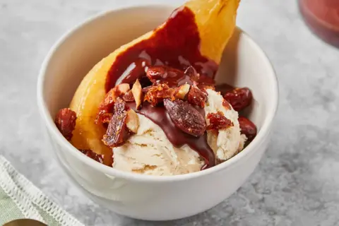 Poire pochée, glace vanille, sauce chocolat et amandes effilées pour une poire Belle Hélène gourmande.