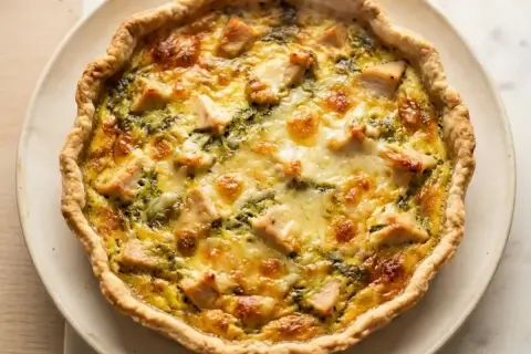 Une délicieuse quiche au poulet, dorée et garnie de morceaux de poulet et de fromage fondant, prête à être dégustée.