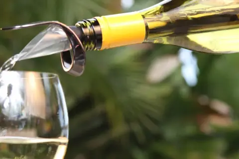 Un vin blanc est versé dans un verre, suggérant le plaisir d'un bon vieillissement du vin.