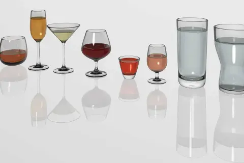 Diversité de verres à vin et à eau, prêts pour un repas au restaurant. Chaque verre présente une quantité différente de liquide.