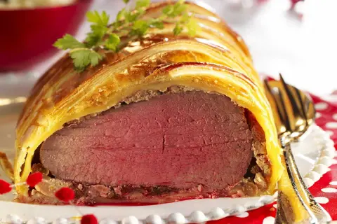 Un magnifique filet mignon en croûte, doré et feuilleté, prêt à être dégusté. Une garniture festive parfaite.