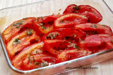 Tomates au four coupées en quartiers, baignant dans leur jus avec des herbes et de l'ail. Un plat simple et savoureux.