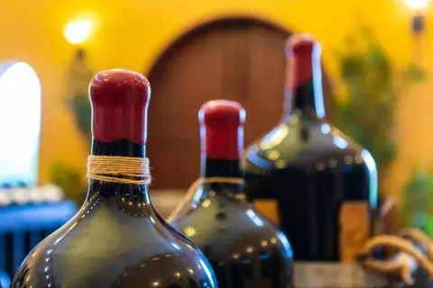 Trois bouteilles de vin, dont une en magnum litres, avec des bouchons rouges et une ficelle autour du col.