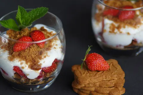 Délicieux tiramisu fraises spéculoos, superposé dans un verre avec des fraises fraîches, de la crème et des miettes de spéculoos.