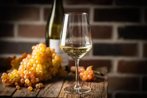 Verre de vin blanc sec, avec des grappes de raisins dorés. Le taux de sucre dans le vin blanc sec est faible, idéal pour accompagner les mets.