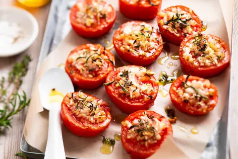 Tomates provençales garnies d'herbes et de fromage, rôties sur une plaque. Un délice méditerranéen.