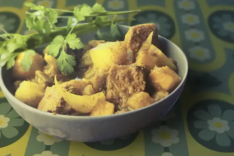 Un bol de colombo de porc, plat épicé et savoureux, garni de coriandre fraîche.