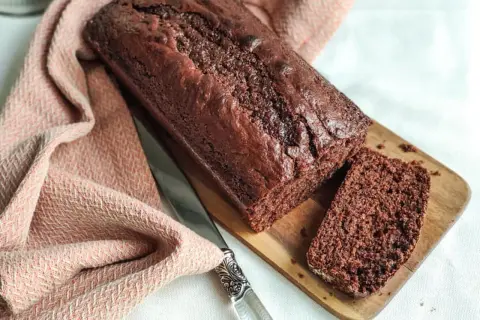 Un délicieux gâteau yaourt chocolat, moelleux et intense, prêt à être dégusté. Une tranche coupée révèle sa texture aérée.