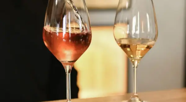 Un verre de vin blanc bouchonné, d'une couleur rosée, est servi dans un verre. Un autre verre de vin blanc est à côté.