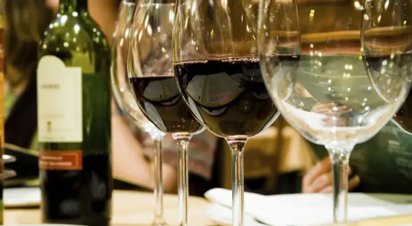 Une bouteille de vin rouge et plusieurs verres remplis de vin à la belle couleur rubis.