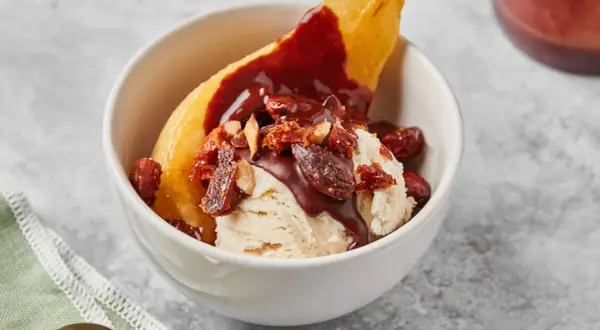 Poire pochée, glace vanille, sauce chocolat et amandes effilées pour une poire Belle Hélène gourmande.
