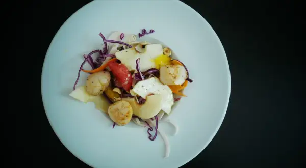 Salade de Saint-Jacques poêlées, avec des fruits et légumes croquants, un délice qui appelle un bon vin blanc.