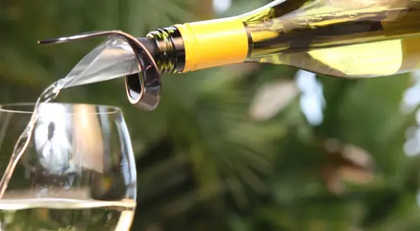 Un vin blanc est versé dans un verre, suggérant le plaisir d'un bon vieillissement du vin.