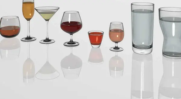Diversité de verres à vin et à eau, prêts pour un repas au restaurant. Chaque verre présente une quantité différente de liquide.