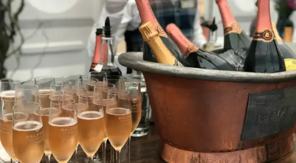Une belle quantité de vin pour un mariage, avec des flûtes remplies de champagne et des bouteilles au frais dans un grand seau en cuivre.