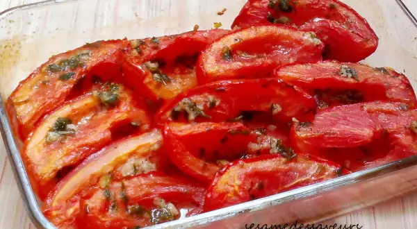 Tomates au four coupées en quartiers, baignant dans leur jus avec des herbes et de l'ail. Un plat simple et savoureux.