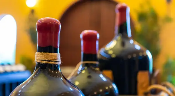Trois bouteilles de vin, dont une en magnum litres, avec des bouchons rouges et une ficelle autour du col.
