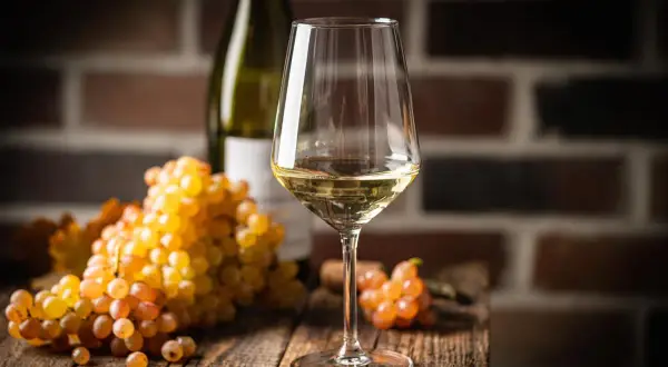 Verre de vin blanc sec, avec des grappes de raisins dorés. Le taux de sucre dans le vin blanc sec est faible, idéal pour accompagner les mets.
